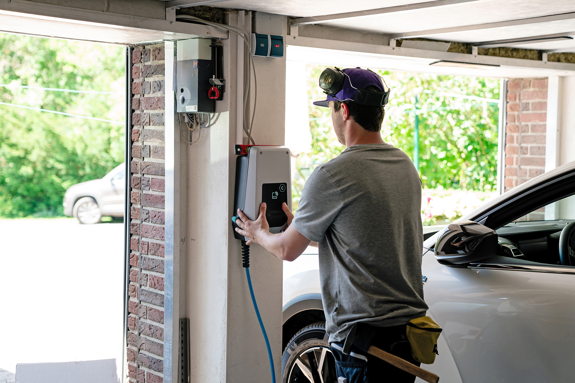 1KOMMA5°-Installateur montiert eine zukunftsweisende Elektrofahrzeug-Ladestation (Wallbox) in einer Garage, um die E-Mobilität zu fördern
