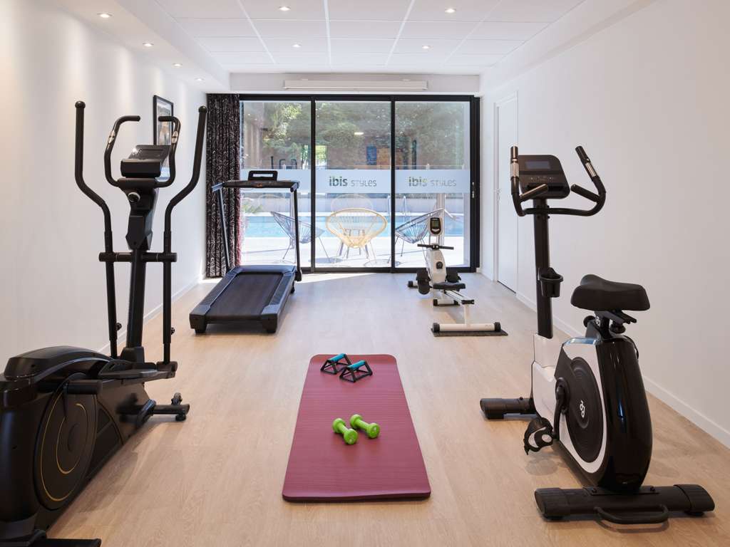 Salle de sport de l'hôtel avec vue sur la piscine extérieure, accessible aux clients pendant leur séjour.